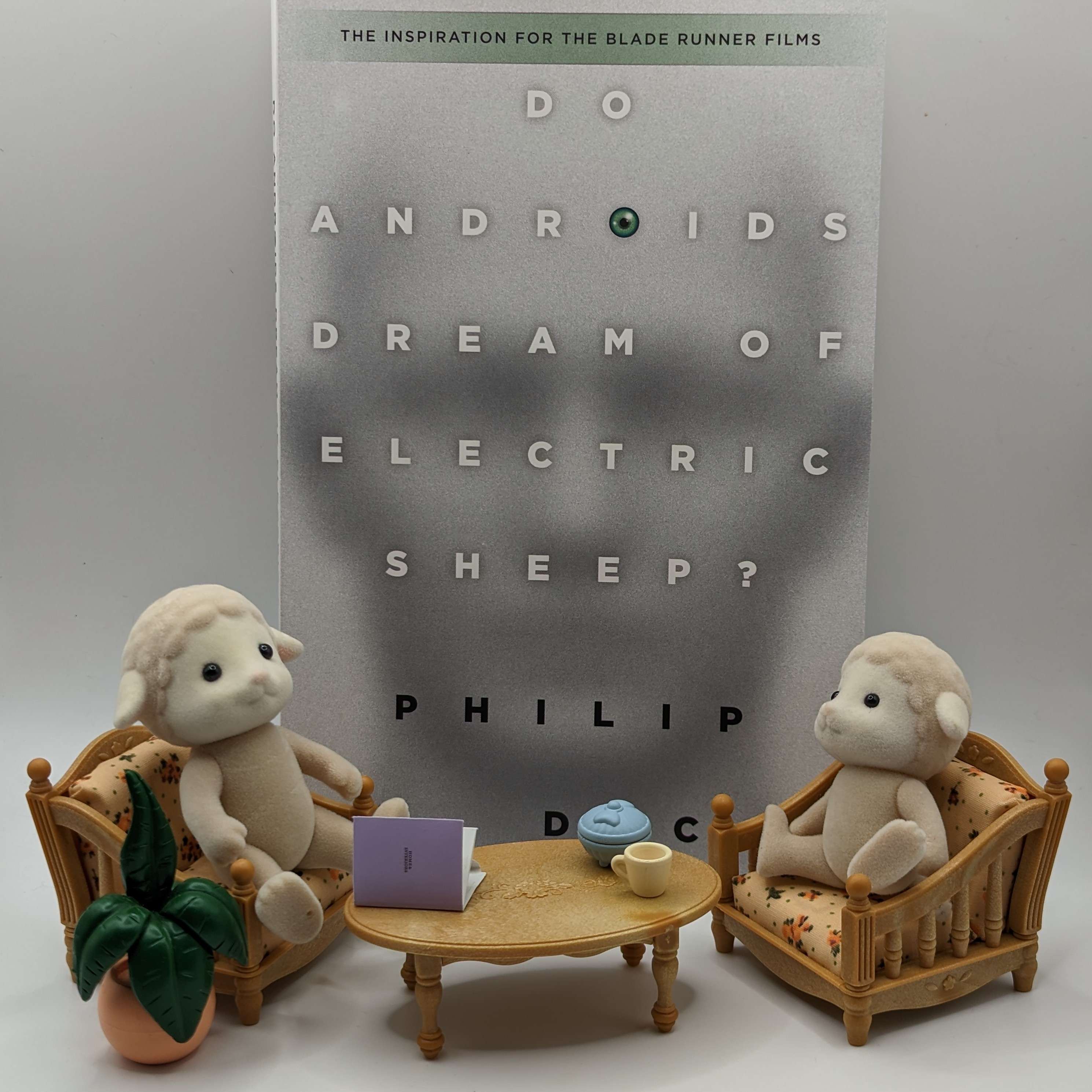Two toy sheeps in front of sci fi book